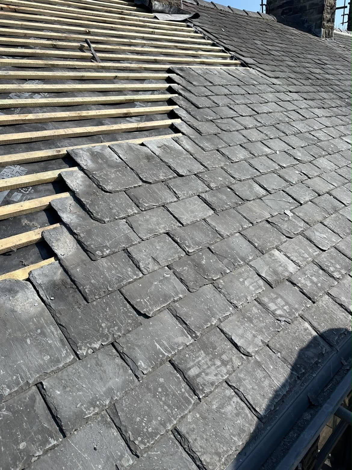 D&M Roofing re-laying reclaimed stone slates over new battens and membrane