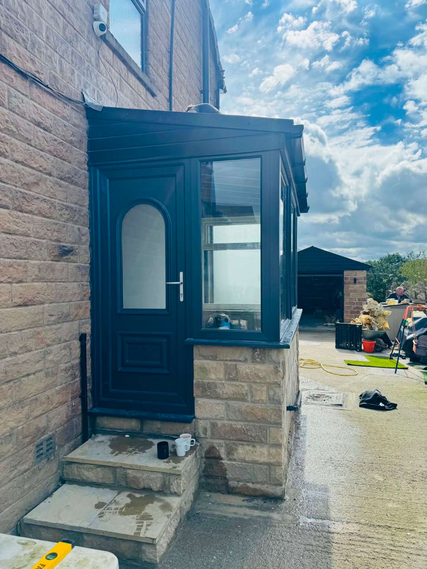 Newly built stone porch with anthracite grey door and windows, viewed from the front