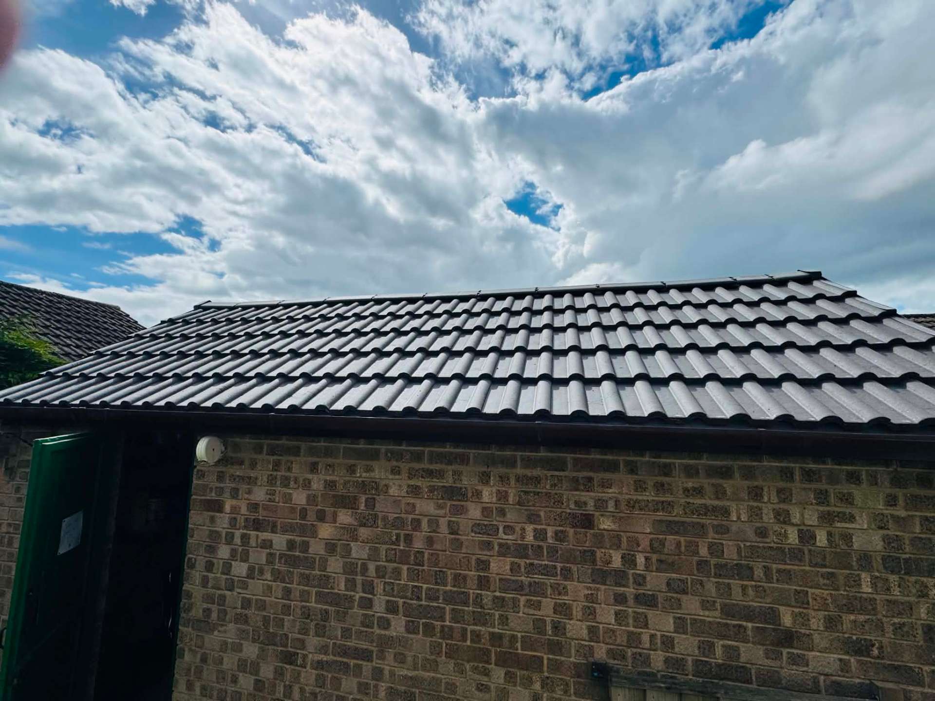 New black pantile roof covering and guttering on a brick garage
