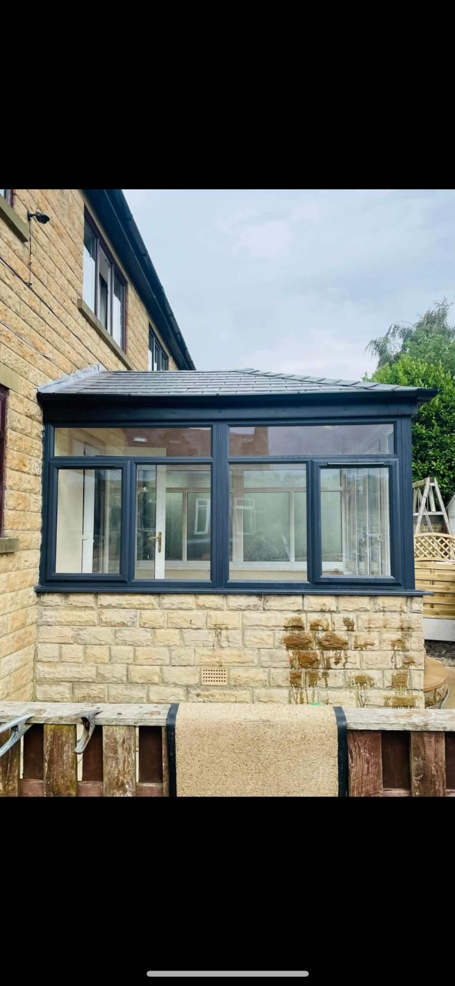 Conservatory with anthracite grey frames and a new solid tiled warm roof on a stone base