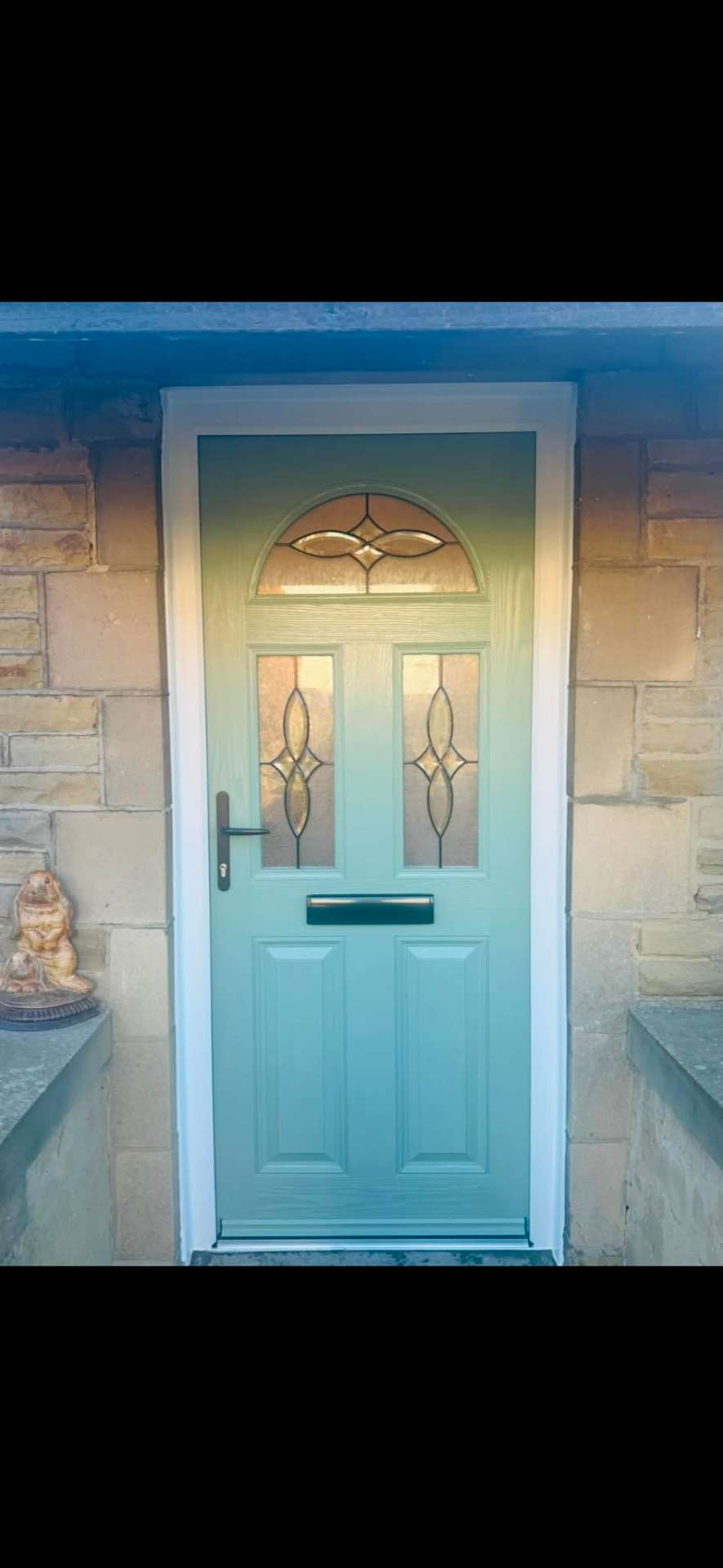Sage green composite front door with decorative leaded glass in a stone surround