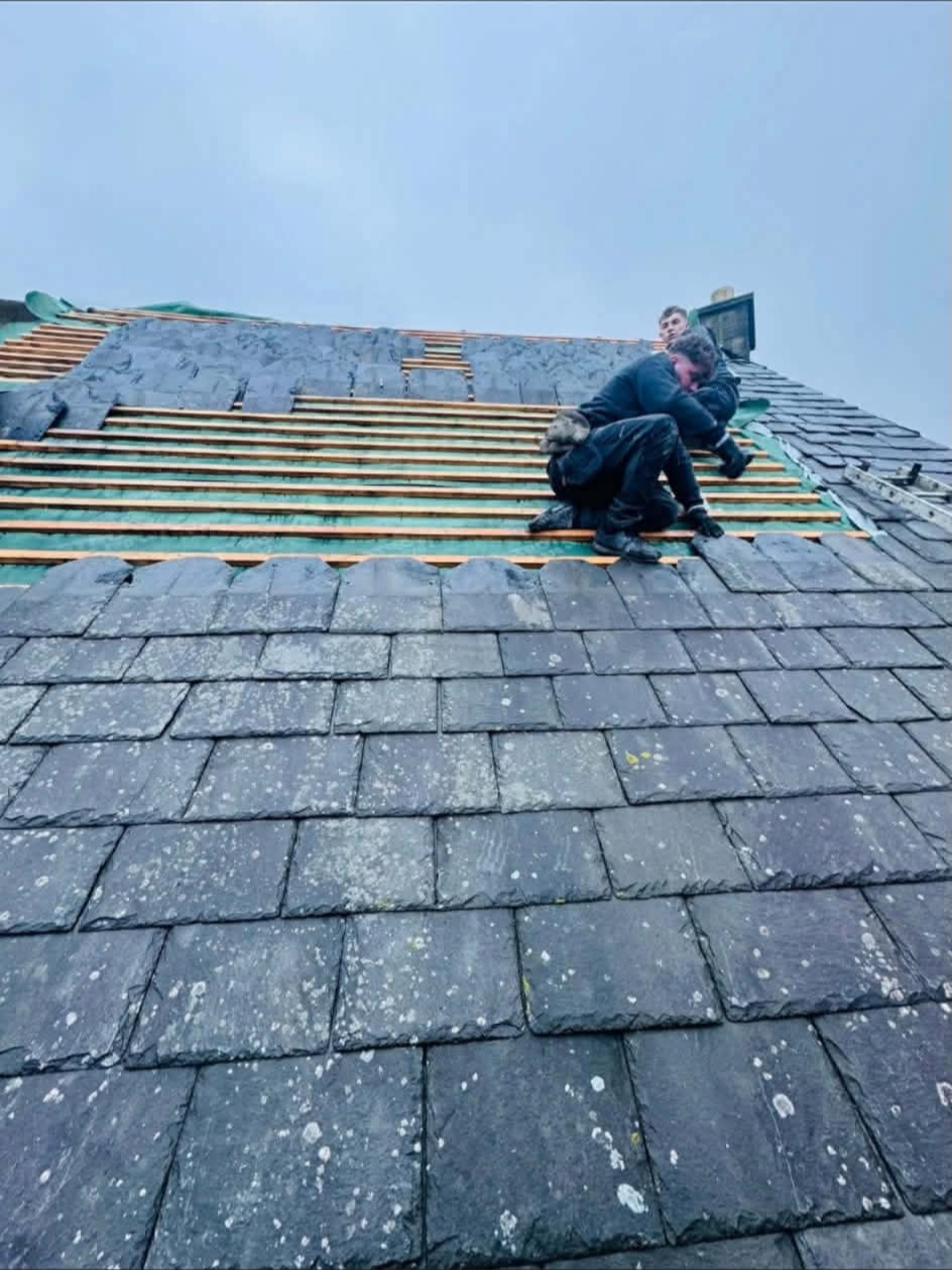 D&M Roofing team re-laying natural slate over new battens and membrane on a steep pitched roof
